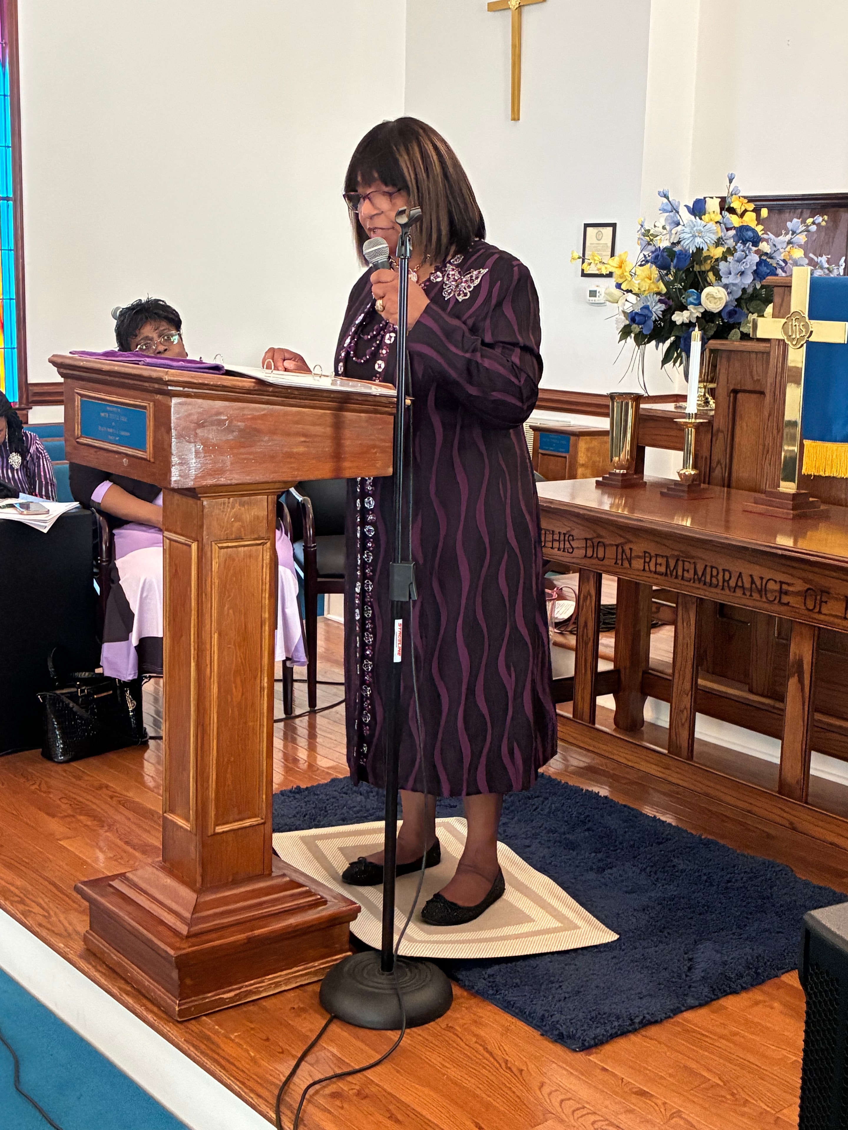 Woman in purple dress speaking at the microphone in the sanctuary